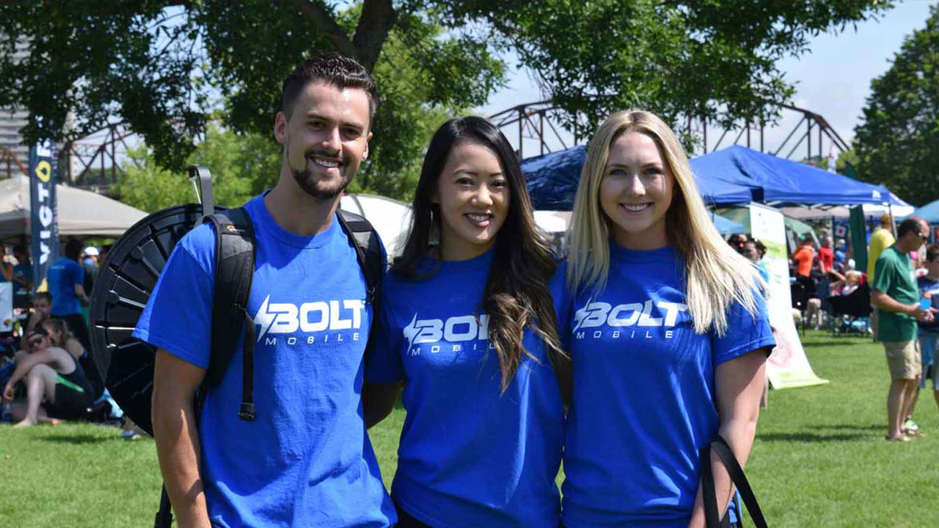 Three Bolt Mobile brand ambassadors wearing blue shirts posing for a picture at community event in the summer